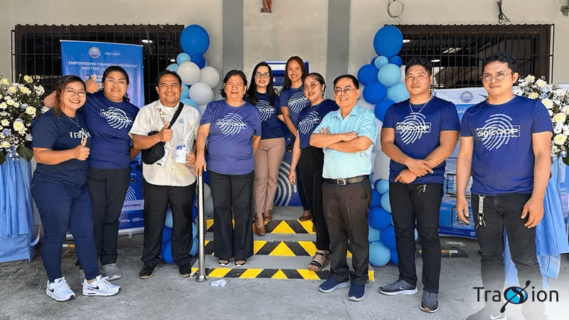 DigiCOOP staff in blue shirts and Candelaria MPC officers at the launch of the cooperative's Cash Teller Machine, framed by blue and white balloons.